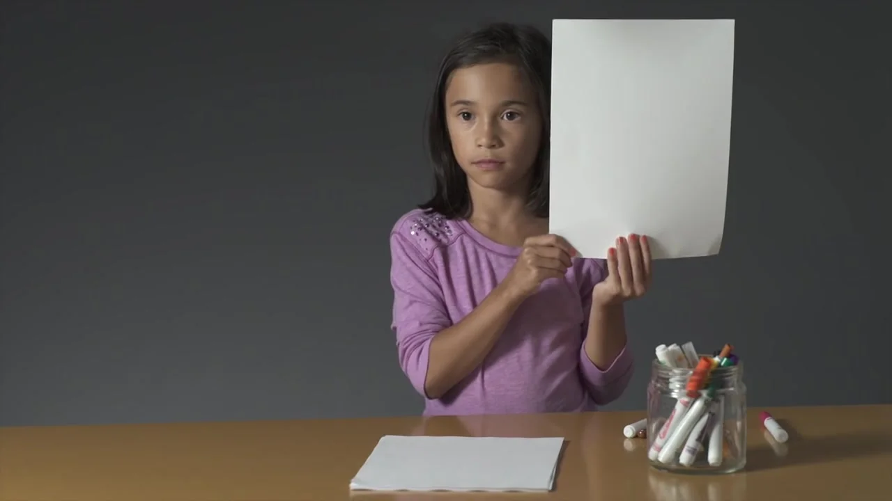A girl holds up a blank sheet of paper — still from Kids Know Breakfast