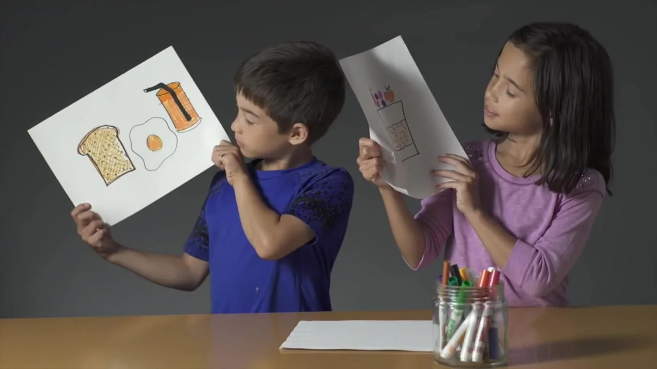 Two kids holding up their breakfast drawings — still from Kids Know Breakfast