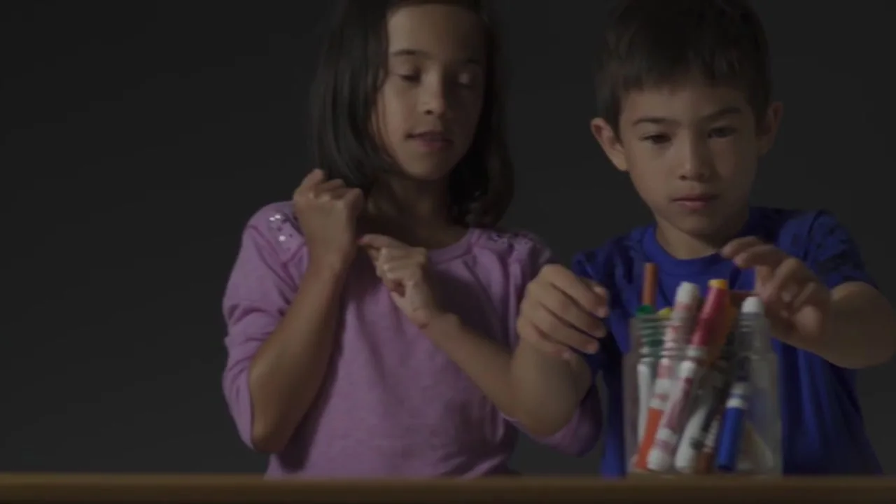 Two kids pick markers from a jar