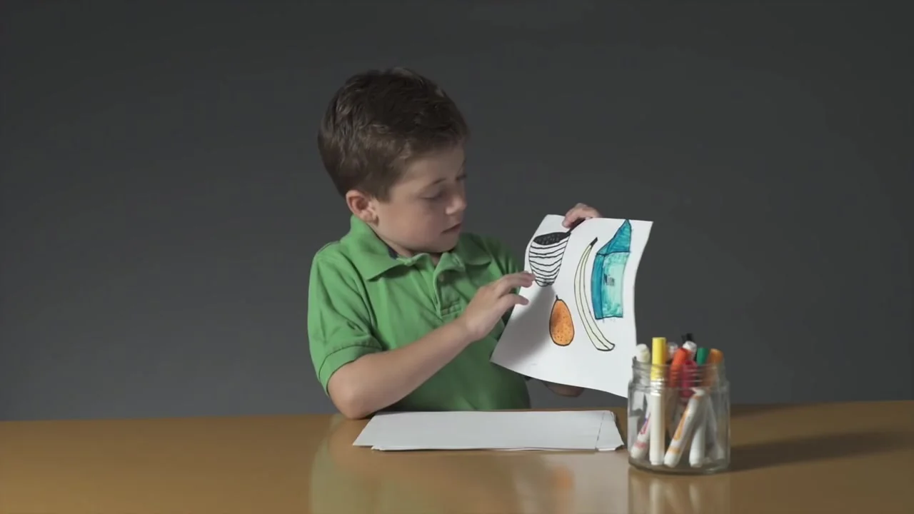 A boy holds up a drawing of his breakfast